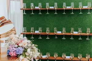 Stand zum Brille. ein luxuriös Hochzeit Zeremonie. romantisch Hochzeit Zeremonie. Champagner Brille auf ein Grün Hintergrund. Hochzeit Einzelheiten foto