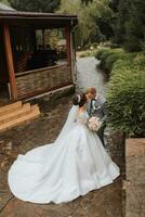 gut aussehend Bräutigam und charmant Braut zusammen im das Park. Porträt. luxuriös Kleid mit ein lange Zug. elegant jung Bräutigam. Hochzeit Strauß. Luxus Hochzeit foto