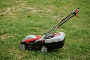 Rasen Mover auf Grün Gras im modern Garten. Maschine zum Schneiden Rasenflächen. Sicherheit Ausrüstung mit Garten Werkzeuge foto