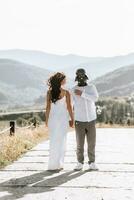 stilvoll Bräutigam im Weiß Hemd und süß Brünette Braut im Weiß Kleid im Wald in der Nähe von Hochzeit hölzern Bogen. Hochzeit Porträt von Jungvermählten. foto