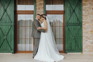 das Braut und Bräutigam sind Stehen gegen das Hintergrund von Grün Fenster. stilvoll Braut und Bräutigam. Hochzeit Foto. einfach Atmosphäre foto