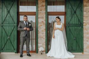 das Braut und Bräutigam sind Stehen gegen das Hintergrund von Grün Fenster. stilvoll Braut und Bräutigam. Hochzeit Foto. einfach Atmosphäre foto