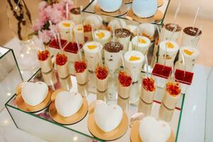 köstlich Hochzeit Rezeption Süßigkeiten Bar Dessert Tabelle voll mit Kuchen und Süßigkeiten und Blumen Chinesisch Kirsche Blüten auf das Hintergrund von ein exquisit Restaurant foto