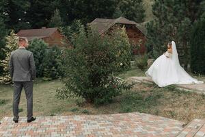 Hochzeit Foto. das Braut und Bräutigam Stand weit ein Teil im das Garten und aussehen beim jeder andere. breit Winkel Foto. Porträt. Hochzeit im Natur. schön Haar und bilden. stilvoll Bräutigam foto