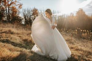 Hochzeit Foto. das Braut und Bräutigam sind Gehen im das Wald. das Braut wirft oben ihr lange Kleid schön. Paar im Liebe. Herbst Hochzeit. foto