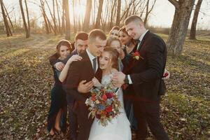 Bräute und freunde im das Natur. freunde beim das Hochzeit. frisch verheiratet Paar, Brautjungfern und Trauzeugen haben Spaß draußen foto