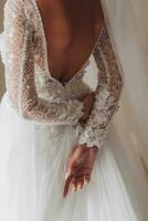 rothaarig Braut im ein schön Kleid, Modell- posieren, Foto von das zurück, Kleid mit ein Schlitz auf das zurück. Hochzeit. Hochzeit Strauß Morgen von das Braut. ein glücklich Braut ist warten zum das Bräutigam.