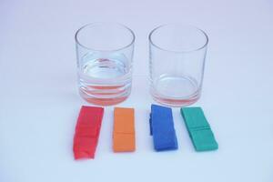 zwei Glas von Wasser und bunt Streifen Papier. Weiß Hintergrund. Ausrüstung bereit zum tun Wissenschaft Experiment Über Chromatographie. einfach Aktivität Chemie Lektion zum Kind. foto