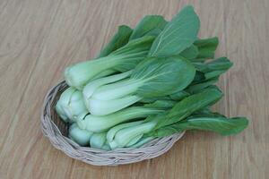 frischer bok choy oder pak choi oder chinakohl auf hölzernem hintergrund und im korb zum kochen. Konzept, Bio-Gemüse. gesundes Essen. hohe Ballaststoffe und Vitamine. foto