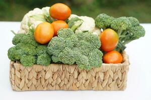 Korb von organisch Gemüse von Garten. Brokkoli, Blumenkohl und Tomaten. draussen Hintergrund. Konzept, Essen Zutat. gesund Essen, Quelle von Vitamine, Ballaststoff und Ernährung. frisch von Garten. foto