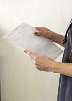 Schuss von das weiblich Arzt im Uniform gegen das Weiß Mauer studieren Kardiogramm. Gesundheitswesen foto