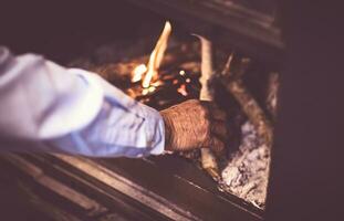 Mann entzünden ein Feuer im das Kamin foto