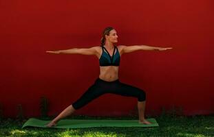 Yoga draußen Über rot Mauer foto