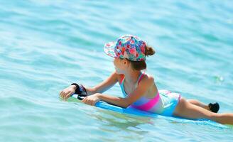 glücklich wenig Mädchen Schwimmen auf das Bodyboard foto