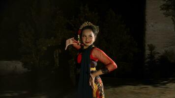ein indonesisch Tänzer strahlt Charme Das zieht an das Beachtung von das Publikum während das Performance mit ihr rot Kleid foto