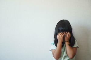 ein verärgert Kind Mädchen Startseite ihr Gesicht mit Hand foto