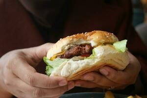 Hand hält Beef Burger auf Tisch Nahaufnahme foto