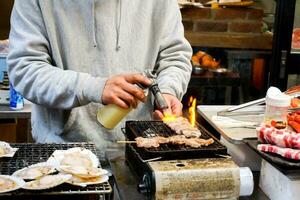 Hand von Koch mit Brenner Kochen und brennen kobe Rindfleisch Holz Stock auf Herd zu Verkauf zum Kunde beim kuromon Markt. kobe Rindfleisch Holz Stock bar-bq ist Beliebt unter Touristen Wer Kommen Sie zu Ausflug beim Osaka Japan. foto