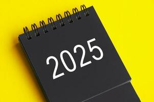 2025 schwarz und Weiß Schreibtisch Kalender auf Gelb Startseite Hintergrund. Neu Jahr Konzept foto