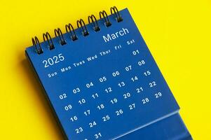März 2025 Blau Schreibtisch Kalender auf Gelb Startseite Hintergrund. foto