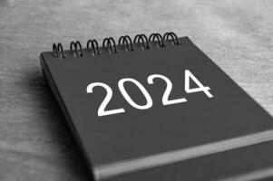 schwarz und Weiß Jahr 2024 Schreibtisch Kalender auf hölzern Schreibtisch. Neu Jahr und Kalender Konzept foto