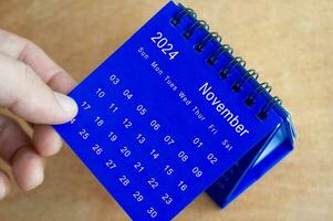 Hand zeigen November 2024 Tabelle Kalender auf hölzern Hintergrund. Kalender und Neu Monat Konzept. foto