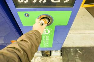 Osaka, Japan 17 kann 2018 - - Hand von einer Menschen entsorgen von Sanft trinken können im das recyceln Müll Maschine zum Tauschen es zu Münzen. foto