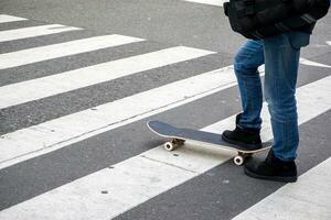 Nahansicht Beine von Teenager spielen ein Skateboard auf Öffentlichkeit Parks Straße. foto