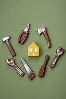 Reparatur oder Zuhause Verbesserung Werkzeuge und ein Haus Modell- auf ein einfach Hintergrund foto