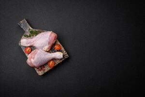 roh Hähnchen Beine mit Salz, Gewürze und Kräuter auf ein dunkel Beton Hintergrund foto