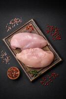 frisches Hühnerfilet auf dunklem Betontisch mit Gewürzen und Kräutern foto