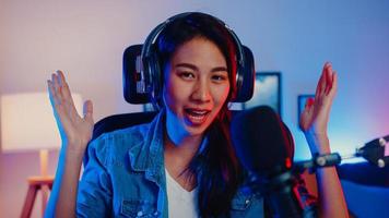 Happy Asia Girl Blogger Music Influencer mit Blick auf die Kamera-Sendungsaufzeichnung tragen Kopfhörer online Live-Gespräch im Mikrofon mit Publikum im Wohnzimmer-Heimstudio in der Nacht. Inhaltsersteller-Konzept. foto