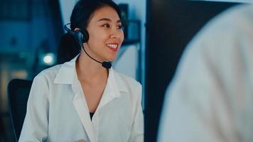 Millennial Asia Young Call Center Team oder Customer Support Service Executive mit Computer- und Mikrofon-Headset, das technische Unterstützung im Late-Night-Büro verwendet. Telemarketing- oder Verkaufsjobkonzept. foto