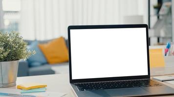 Computer-Laptop mit leerem weißen Bildschirm Mock-up-Display für Werbetext auf dem Schreibtisch im Wohnzimmer im modernen Haus. Chroma-Key-Technologie, Marketing-Design-Konzept.