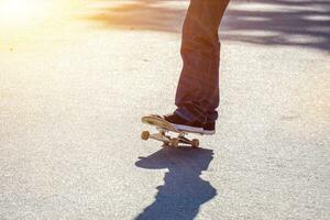 Nahansicht Beine von Teenager spielen ein Skateboard auf Öffentlichkeit Parks Straße. foto