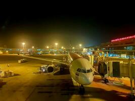 Bangkok Stadt, Thailand, 2019 - - Landschaft Aussicht von draußen Terminal Don mueang International Flughafen mit thailändisch Flugzeug kommt an und geparkt liefert Passagier mit Jet Brücke auf Nacht Zeit. foto