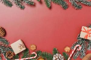 minimale kreative flache Lage von traditioneller Weihnachtskomposition und Neujahrsferienzeit. Draufsicht Winterweihnachtsdekorationen auf rotem Hintergrund mit Leerzeichen für Text. Raumfotografie kopieren. foto