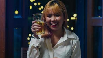 junge asiatische dame trinkt bier und hat spaß fröhliche nacht party neujahrsveranstaltung online feier per videoanruf per telefon zu hause nachts. soziale Distanz, Quarantäne für Coronavirus. Standpunkt oder Standpunkt