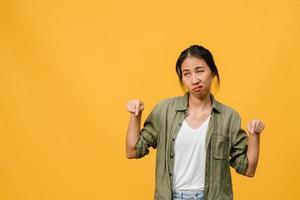 Junge asiatische Dame zeigt etwas Erstaunliches im leeren Raum mit negativem Ausdruck, aufgeregtem Schreien, weinen emotional wütend in Freizeitkleidung einzeln auf gelbem Hintergrund. Gesichtsausdruck Konzept.