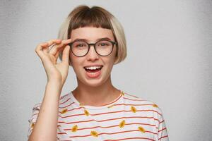 Nahansicht von fröhlich schön jung Frau trägt gestreift t Hemd und Brille fühlt sich glücklich und Lachen isoliert Über Weiß Hintergrund foto