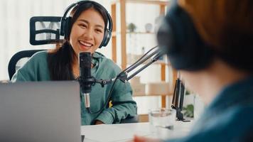 asia girl radio host record podcast verwenden mikrofon tragen kopfhörer interview prominenter gastinhalt gespräch sprechen und in ihrem zimmer zuhören. Audio-Podcast von zu Hause, Sound-Equipment-Konzept.