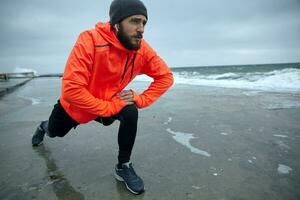 Porträt von aktiv attraktiv jung bärtig Mann Dehnen Muskeln und tun sich warm laufen Vor Morgen laufen, beginnend Tag von Morgen Joggen. Fitness und Sport Konzept foto