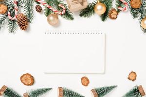 minimale kreative flache Lage der traditionellen Winterweihnachtskomposition und der Neujahrsferienzeit. Ansicht von oben offenes Mockup schwarzes Notebook für Text auf weißem Hintergrund. Mock-up und kopieren Sie Raumfotografie. foto