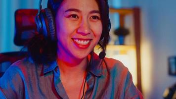 Happy Asia Professional Girl Gamer tragen Kopfhörer Teilnahme spielen Videospiel bunte Neonlichter Computer im Wohnzimmer zu Hause. Esport-Streaming-Spiel online, Heimquarantäne-Aktivitätskonzept. foto