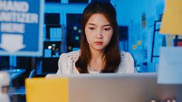Freiberufliche asiatische Frauen, die harte Arbeit des Laptops im neuen normalen Heimbüro verwenden. Arbeiten von Hausüberlastung in der Nacht, Fernarbeit, Selbstisolation, soziale Distanzierung, Quarantäne zur Vorbeugung von Corona-Viren.