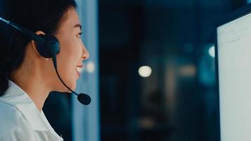 Millennial Asia Young Call Center Agent oder Customer Support Service Executive mit Computer- und Mikrofon-Headset, das technische Unterstützung im Late-Night-Büro verwendet. Telemarketing- oder Verkaufsjobkonzept. foto