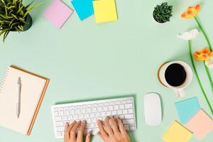 kreatives flaches Laienfoto des Arbeitsplatzschreibtisches. Schreibtisch von oben mit Tastatur, Maus und offenem schwarzen Notizbuch auf pastellgrünem Hintergrund. Draufsichtmodell mit Kopienraumfotografie.