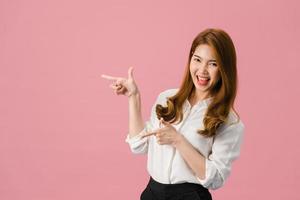 Porträt einer jungen asiatischen Dame, die mit fröhlichem Ausdruck lächelt, zeigt etwas Erstaunliches an Leerzeichen in Freizeitkleidung und blickt auf die Kamera einzeln auf rosafarbenem Hintergrund. Gesichtsausdruck Konzept.