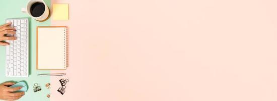 kreatives flaches Laienfoto des Arbeitsplatzschreibtisches. Schreibtisch von oben mit Tastatur, Maus und offenem Mockup-Schwarz-Notizbuch auf pastellgrünem rosafarbenem Hintergrund. Draufsichtmodell mit Kopienraumfotografie. foto