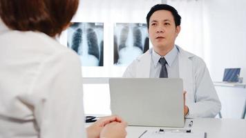 Ein seriöser asiatischer männlicher Arzt in weißer medizinischer Uniform mit Computer-Laptop liefert großartige Neuigkeiten. foto